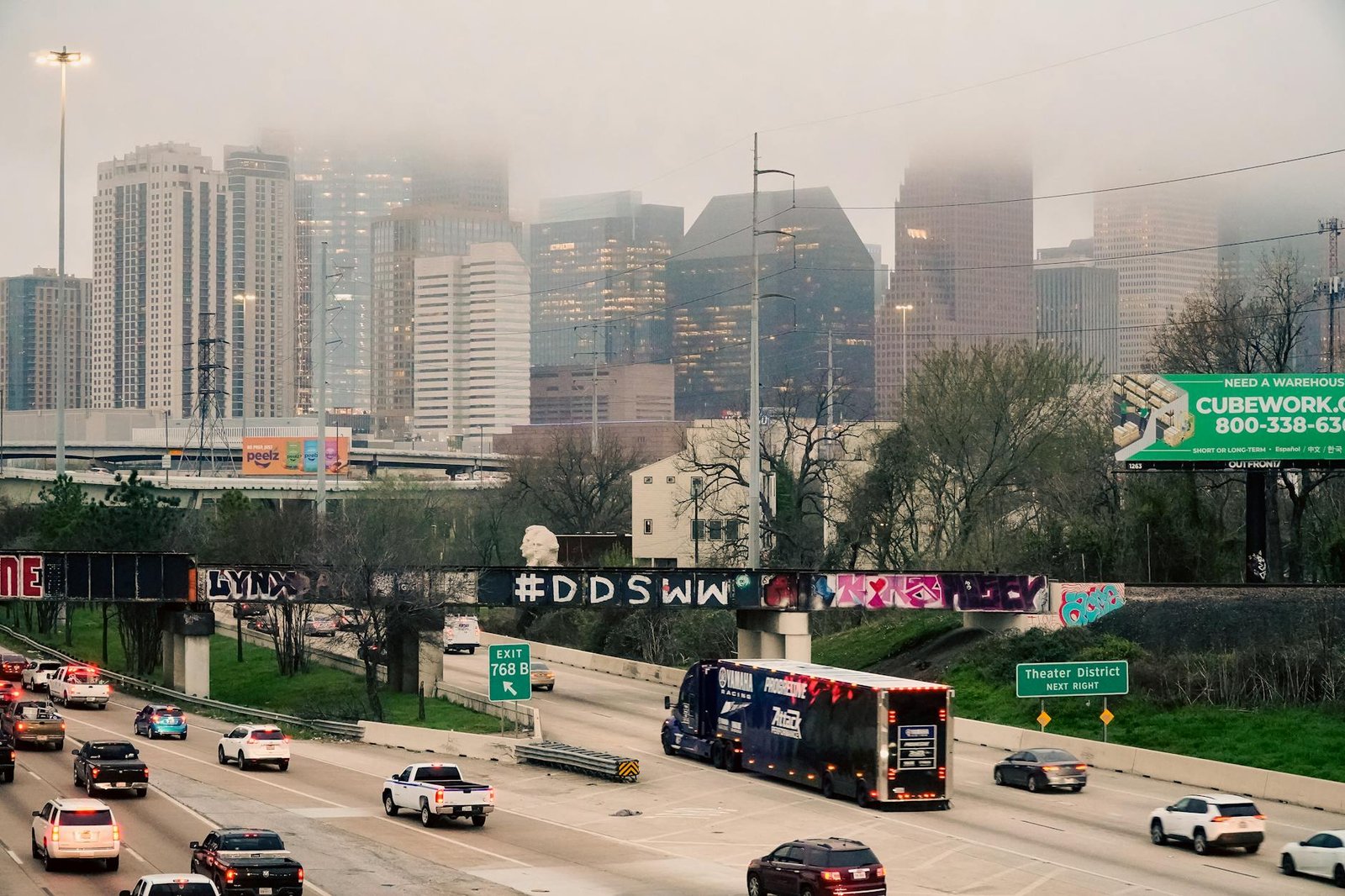 Commuters on a foggy morning with Houston skyline partially obscured by dense fog.