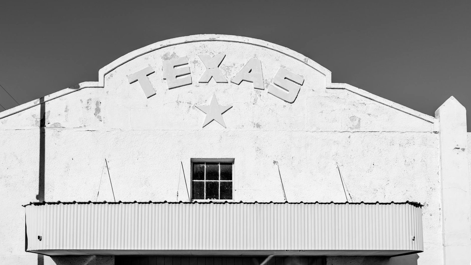 Black and white image of a rustic Texas facade in Marfa with a star design.