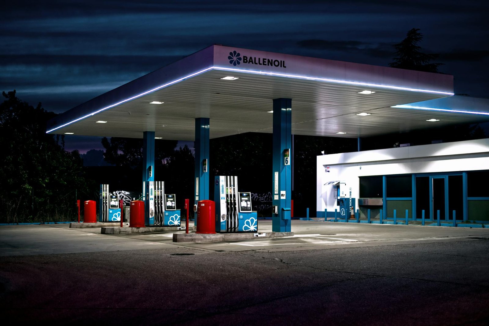 A brightly lit gas station under the night sky with an empty forecourt.