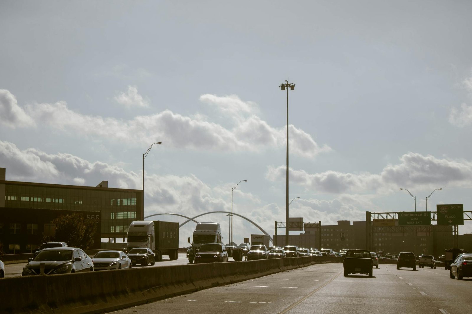 Traffic flows on a Dallas highway under a cloudy sky with visible city skyline. Perfect for urban lifestyle themes.