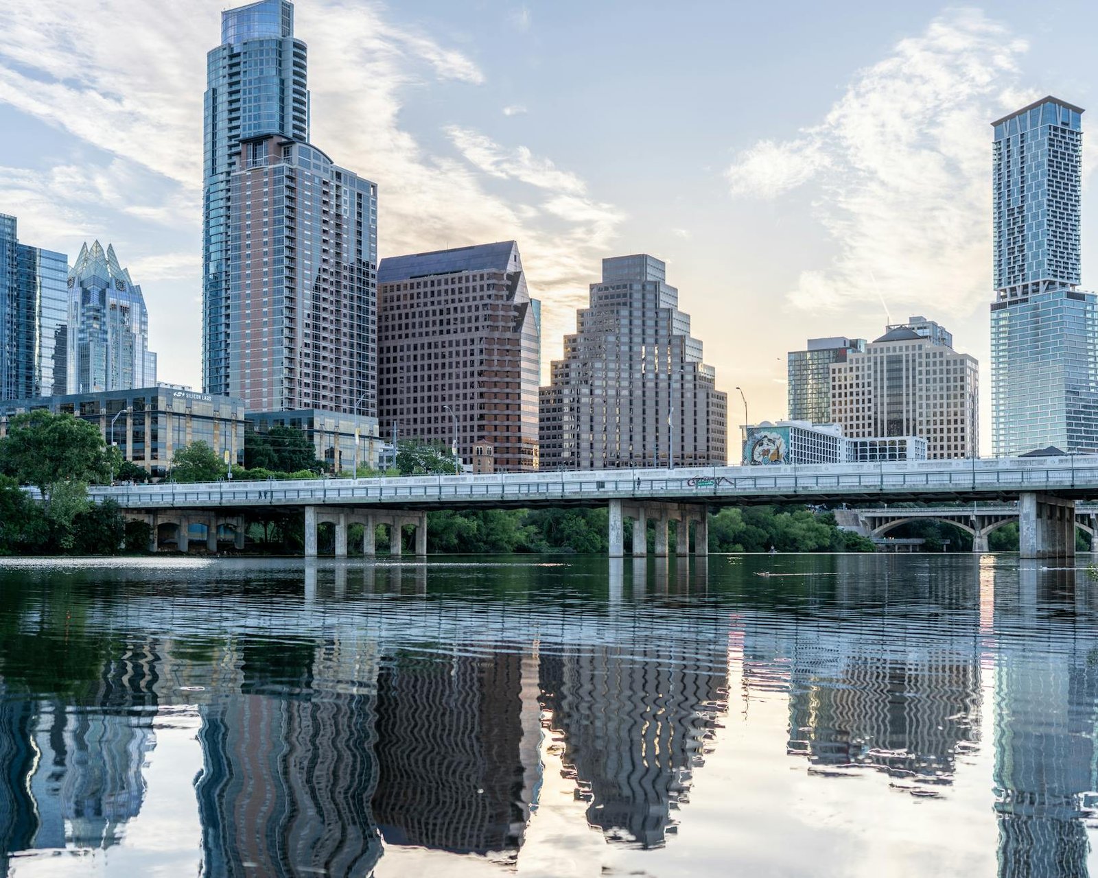 Beautiful view of Austin's skyline with reflections in Lady Bird Lake during daytime.