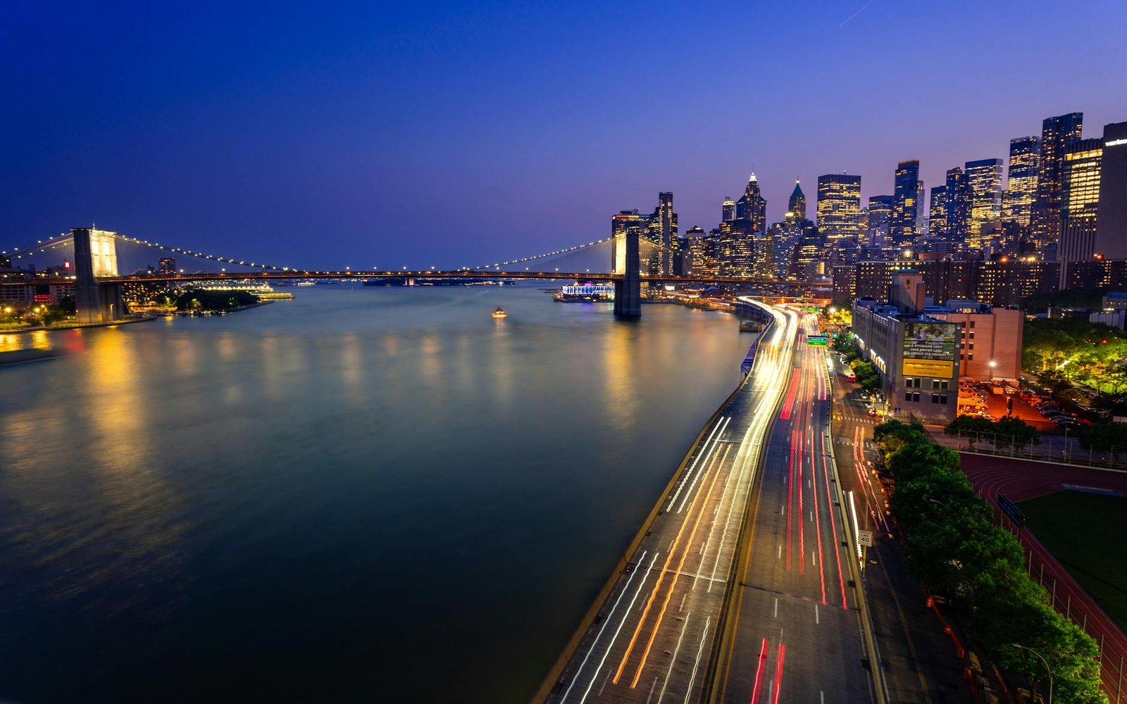 Captivating view of Brooklyn Bridge and Manhattan skyline at dusk, showcasing the vibrant lights of New York City.