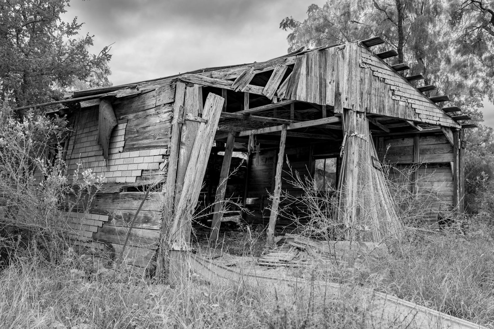 A black and white photo of a weathered, abandoned wooden shack in rural Texas.