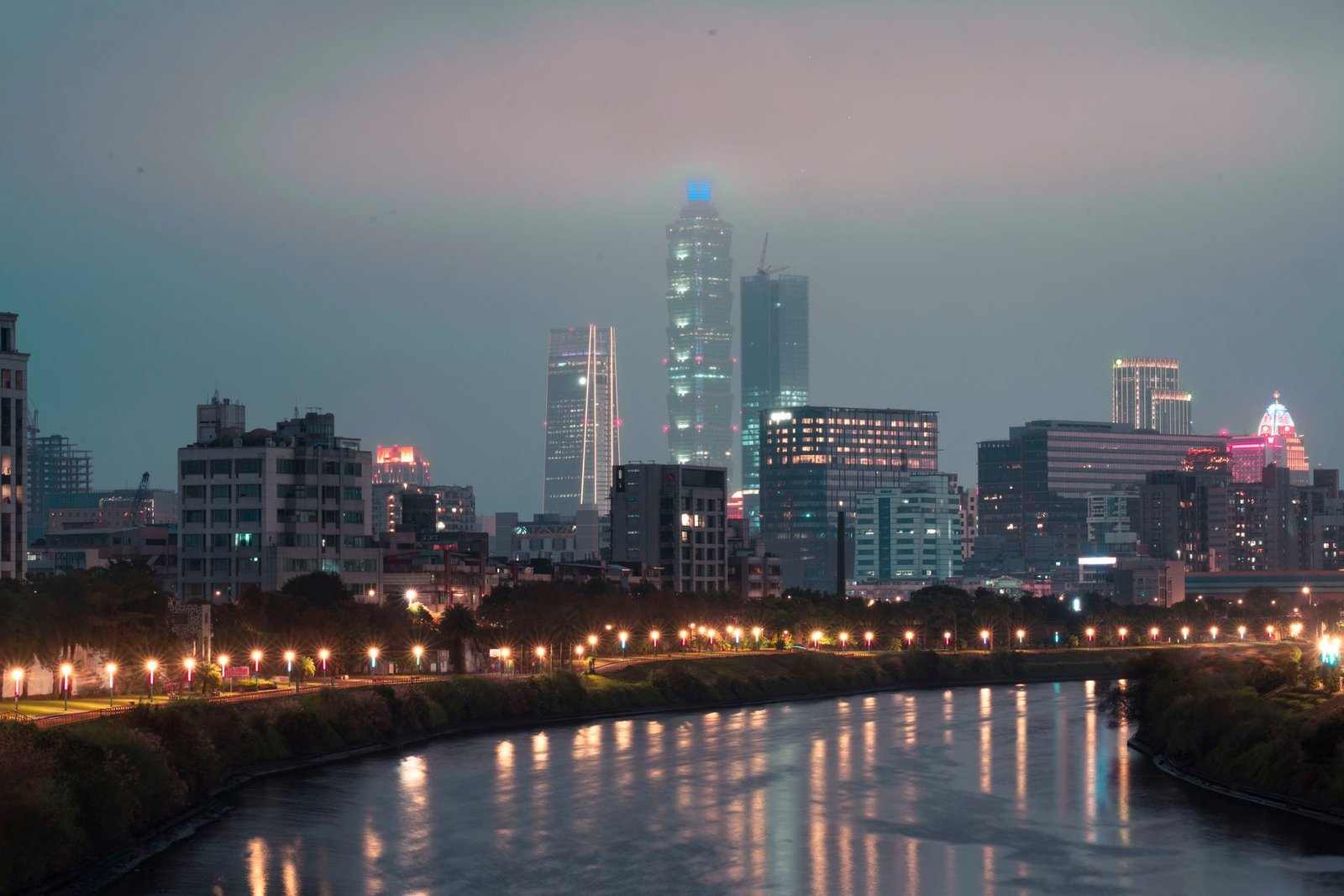 Majestic city skyline along the river, glowing with vibrant lights during nighttime.